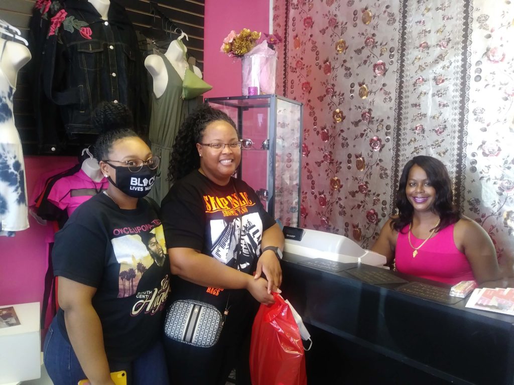 Rosa Jordan with customers after purchase in women's boutique.