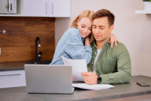 Couple reading documents, insurance papers in front of laptop computer