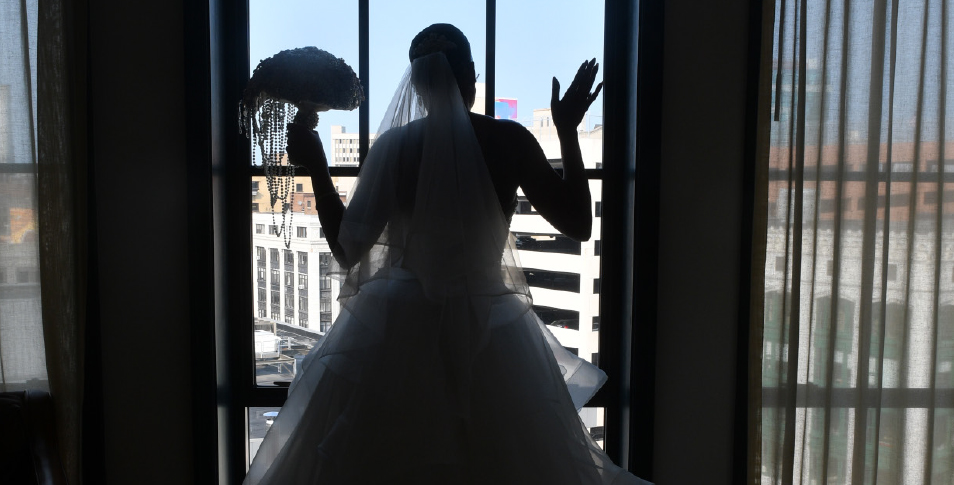 Bride looking out window by professional photographer AM & FM Photography.